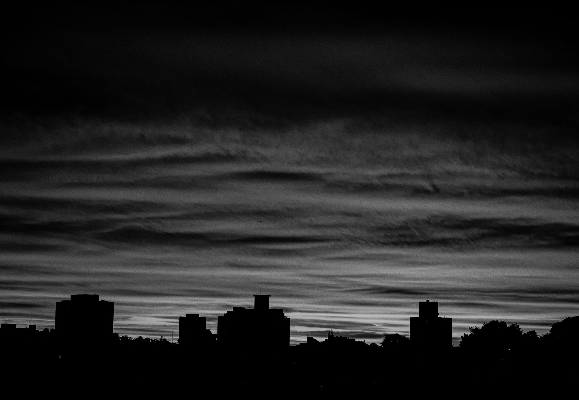 A dramatic black and white city skyline silhouette with a moody twilight sky.